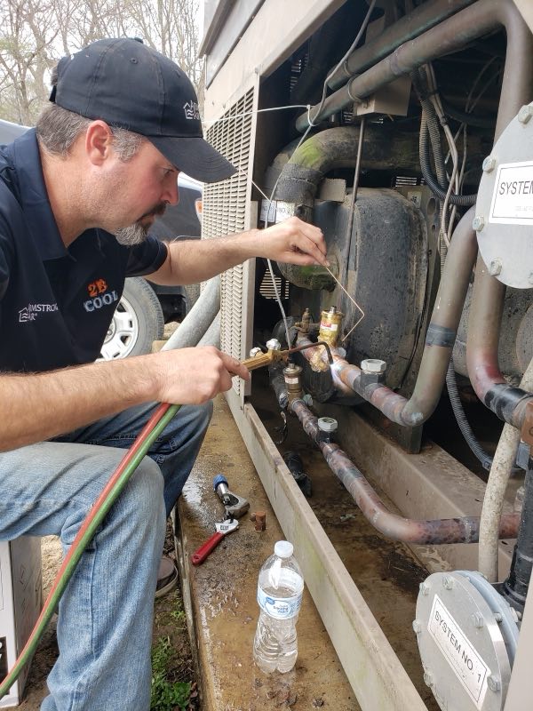 2B Cool HVAC technician servicing a commercial cooling system with gauges